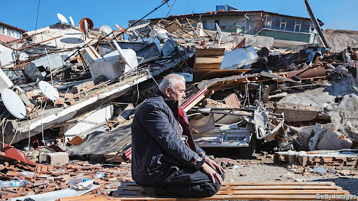 A man sits among the wreckage caused by the 7.8 magnitude earthquake. Credit: The Economist.